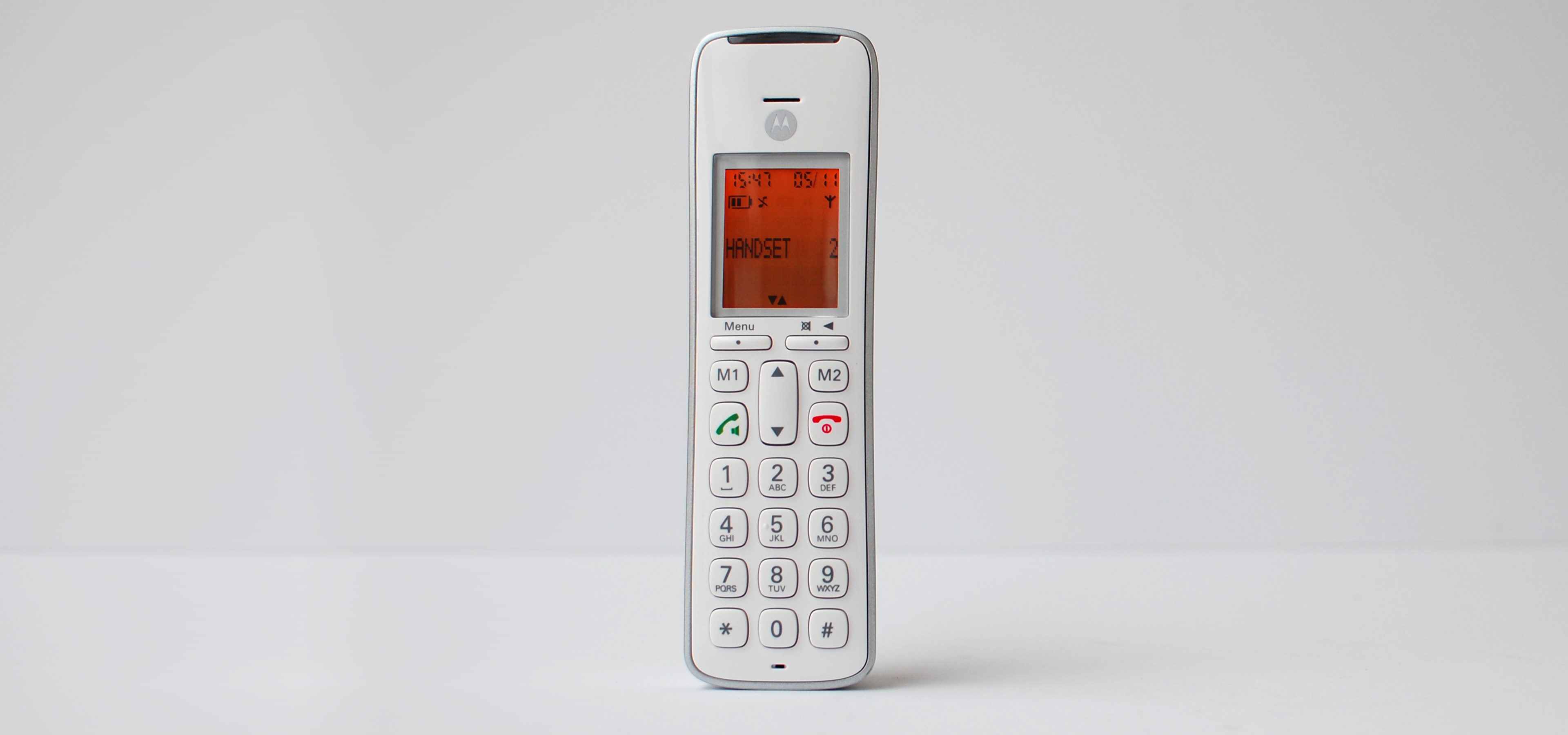 Promoting inclusivity through age-neutral design with SGW Global. Side view of the CD111 Telephone designed by Rodd for SGW GLOBAL.White handset on a pale grey backdrop illumintaed with an orange screen