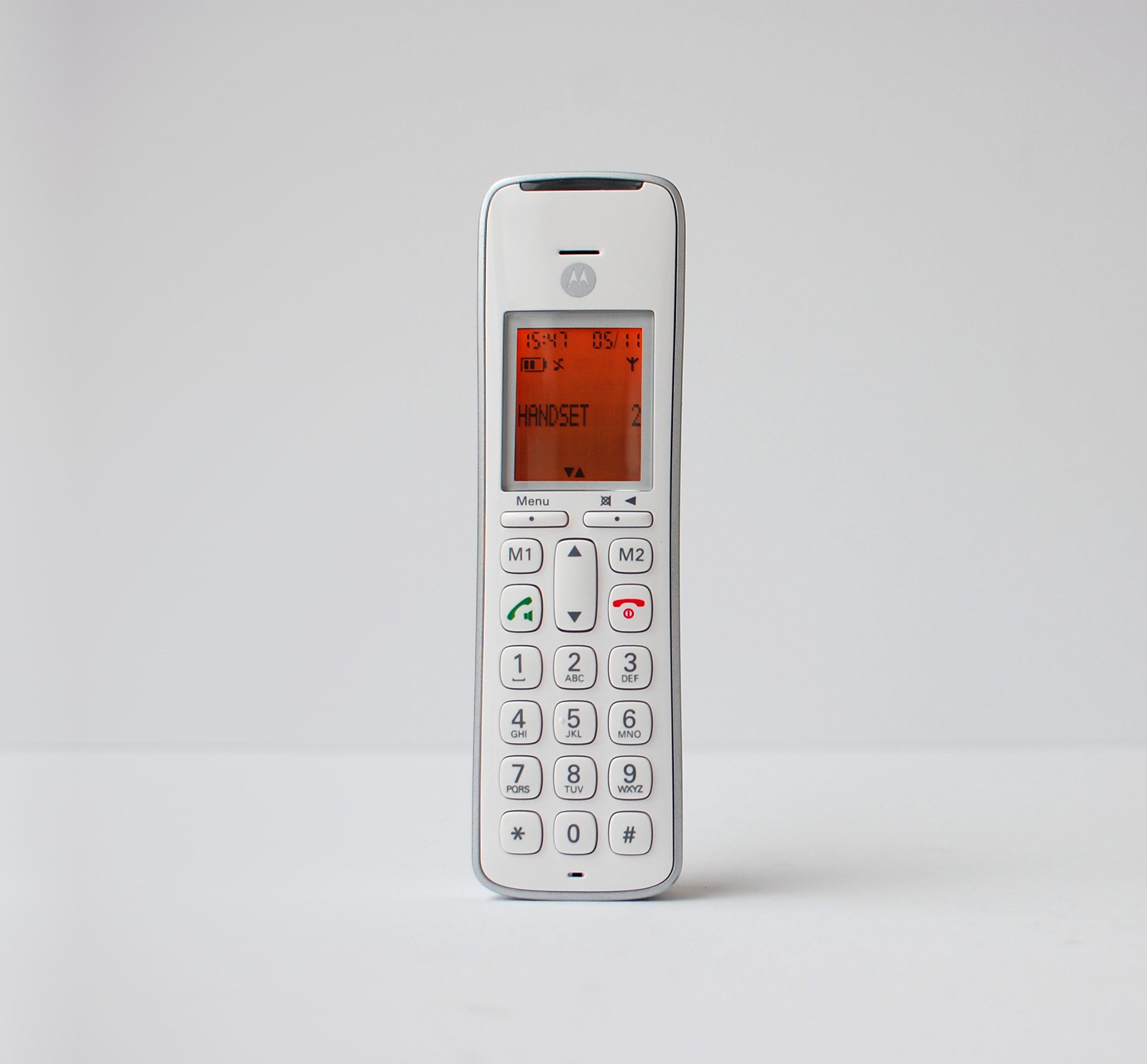 Promoting inclusivity through age-neutral design with SGW Global. Side view of the CD111 Telephone designed by Rodd for SGW GLOBAL.White handset on a pale grey backdrop illumintaed with an orange screen