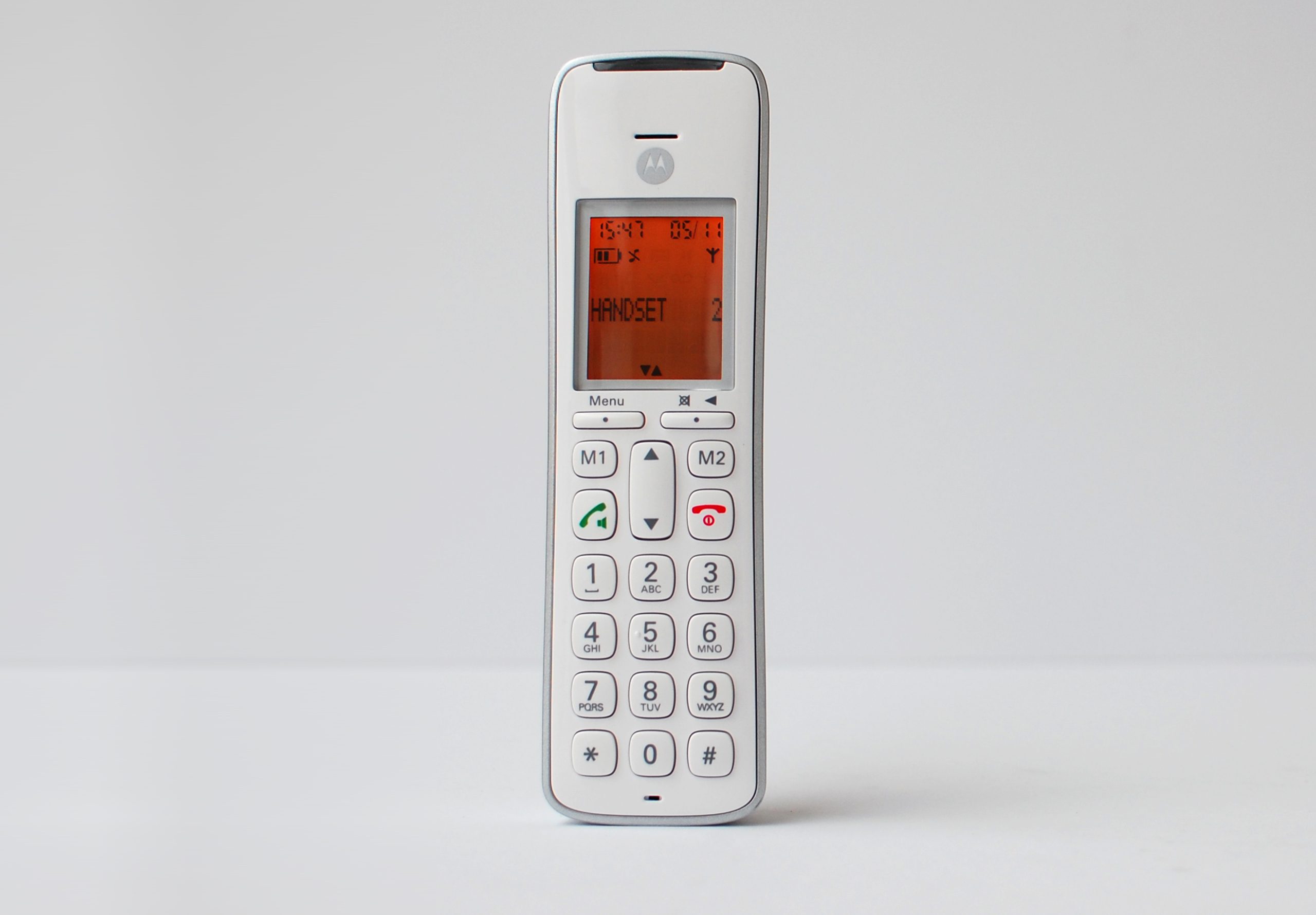 Promoting inclusivity through age-neutral design with SGW Global. Side view of the CD111 Telephone designed by Rodd for SGW GLOBAL.White handset on a pale grey backdrop illumintaed with an orange screen