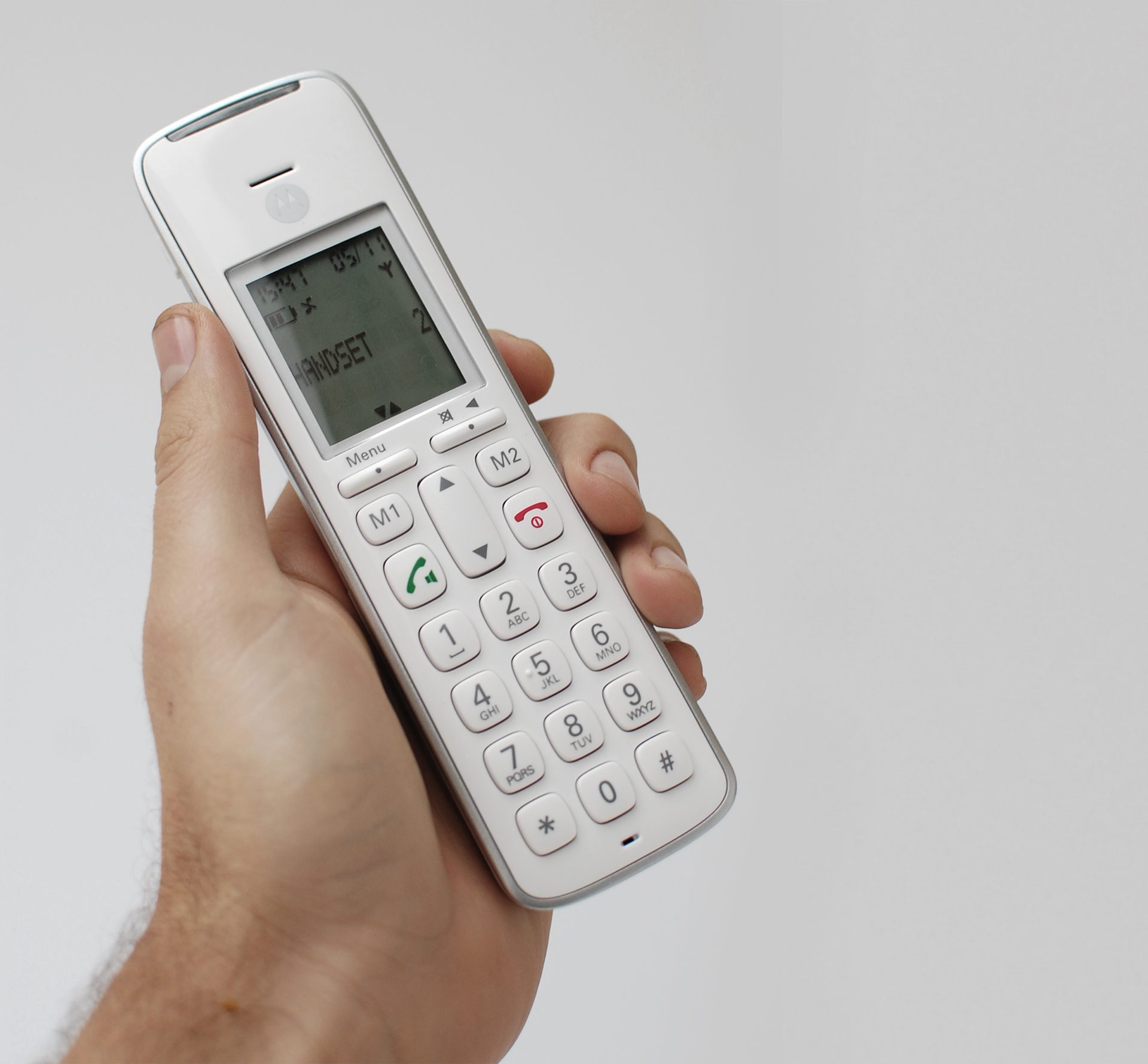 Promoting inclusivity through age-neutral design with SGW Global. Side view of the CD111 Telephone designed by Rodd for SGW GLOBAL.White handset in hand on a pale grey backdrop.