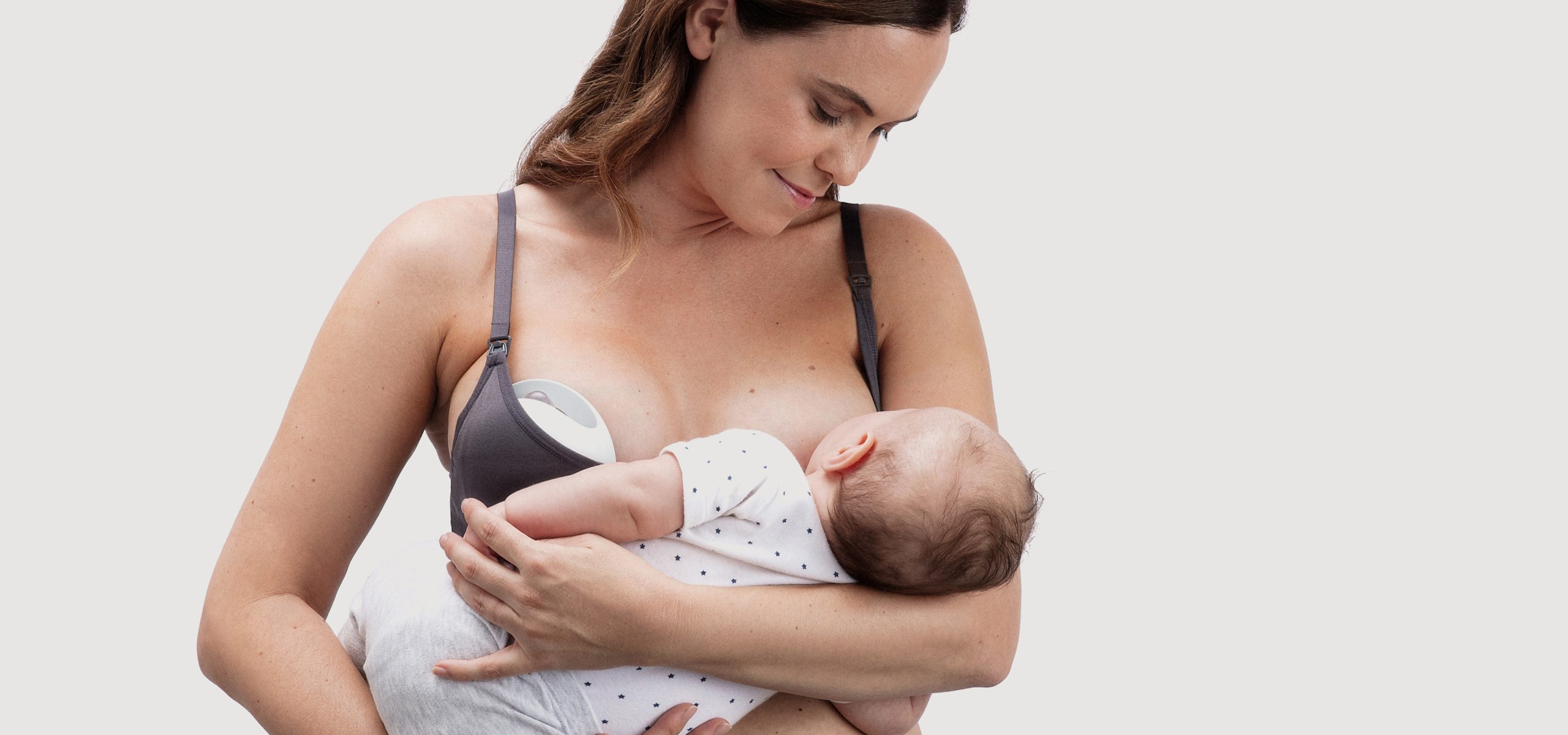 Woman breastfeeding with elvie curve on opposite breast