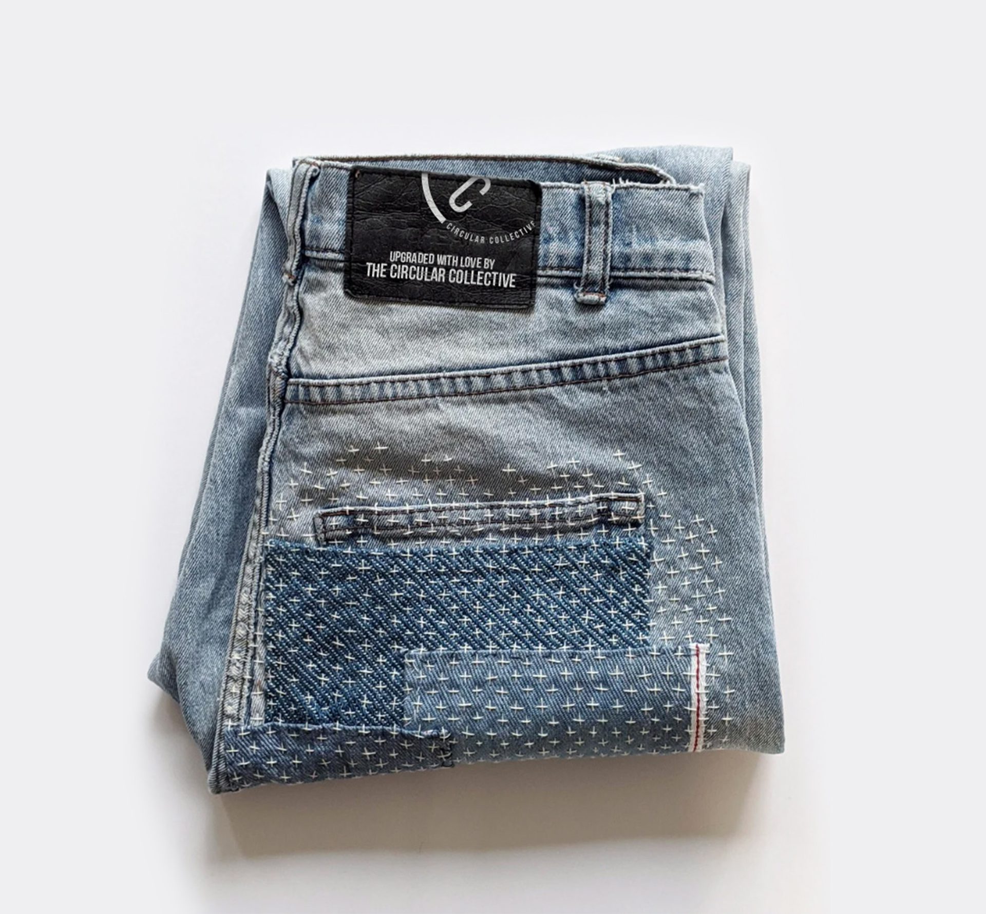 an image of a folded pair of preloved, customedised jeans with the Circular Collective brand