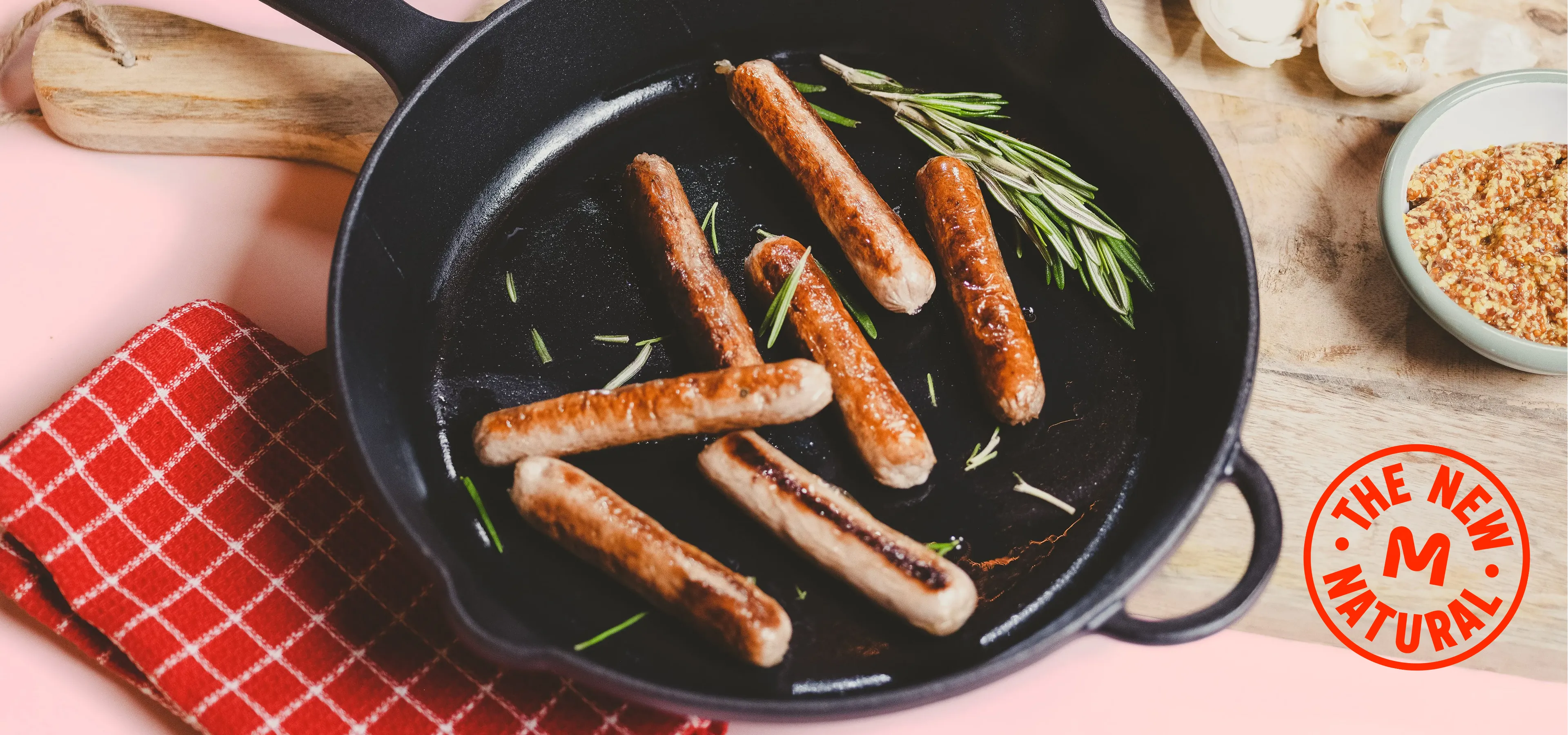 A cast iron pan with frying meatless sausages