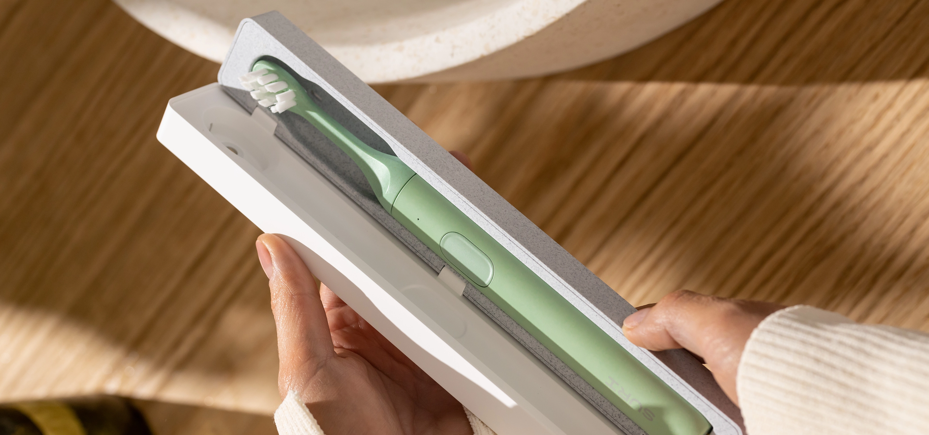 Sage green SURI toothebrush in its charging case