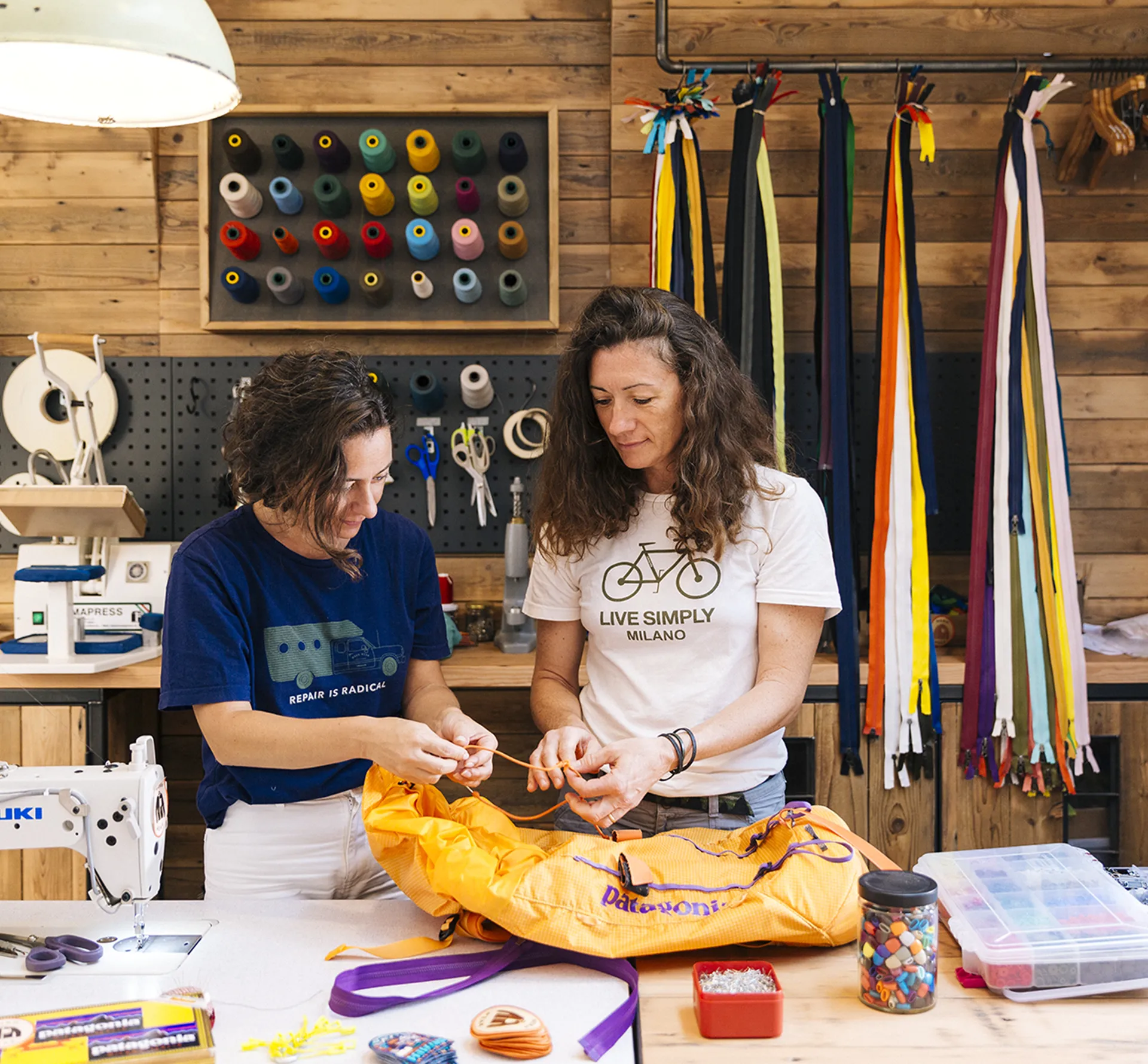 A view inside the Patagonia repair shop with two employees repairing a bag