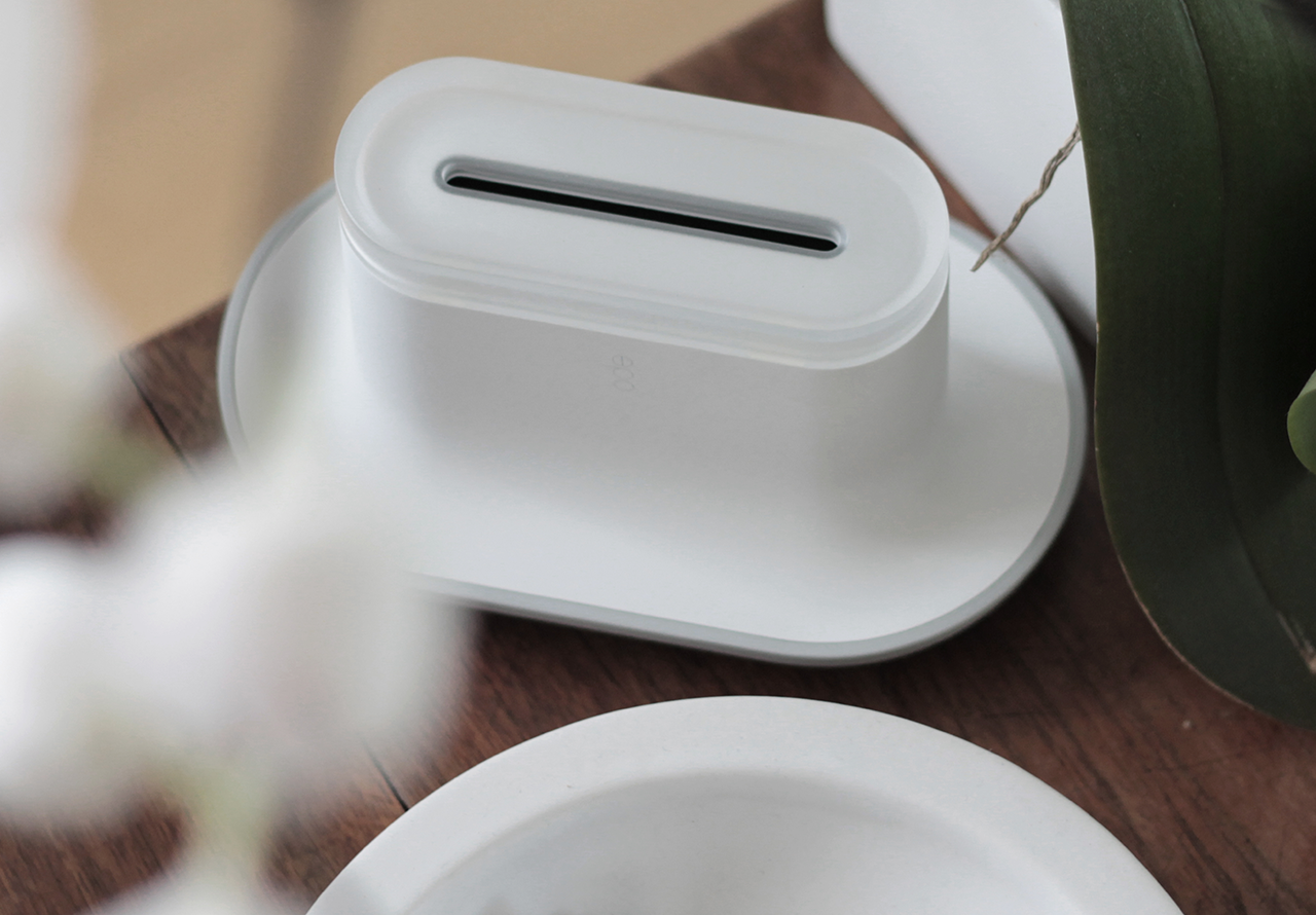 a white ode product on a wooden table surrounded by white blossom