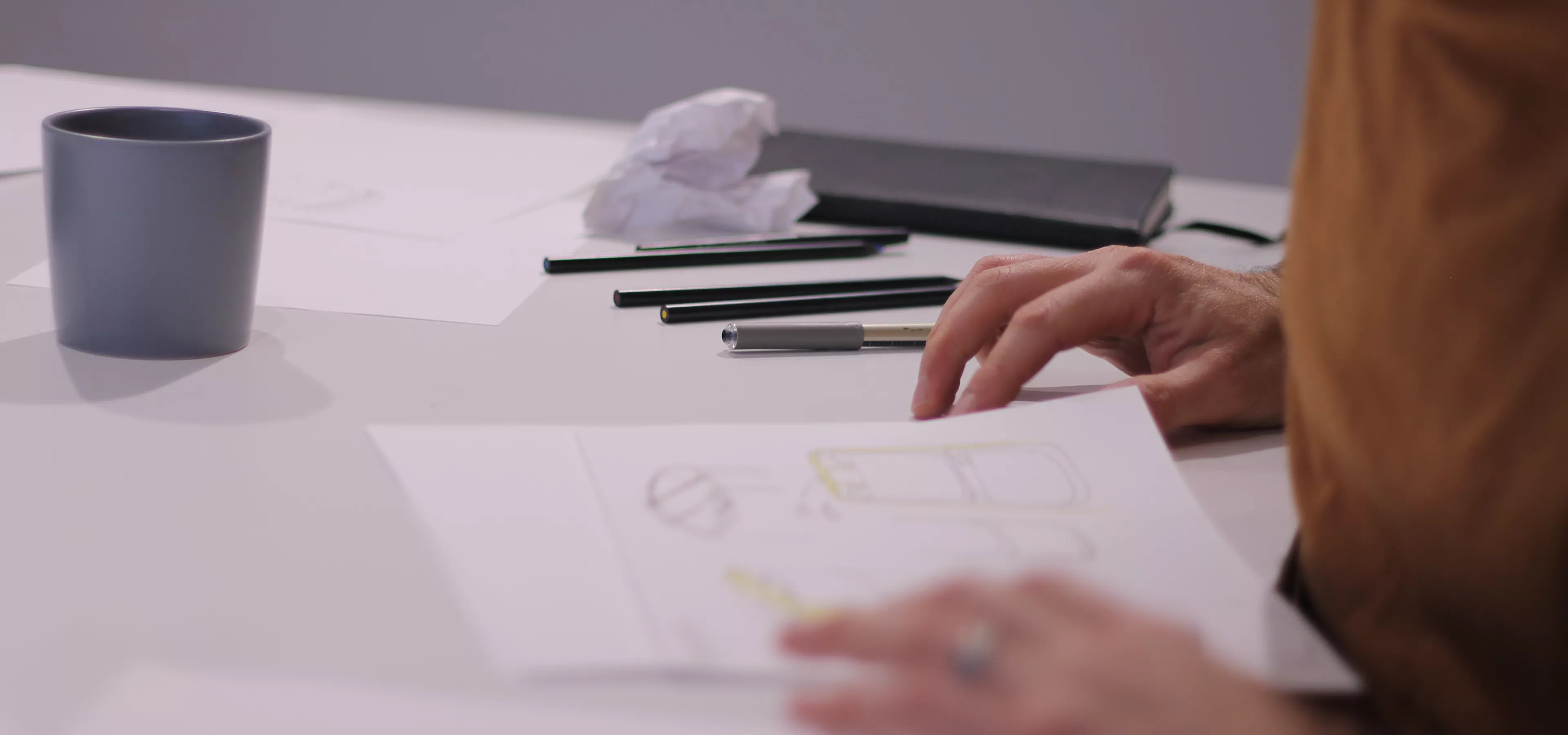 Designer sat at table surrounded by sketches