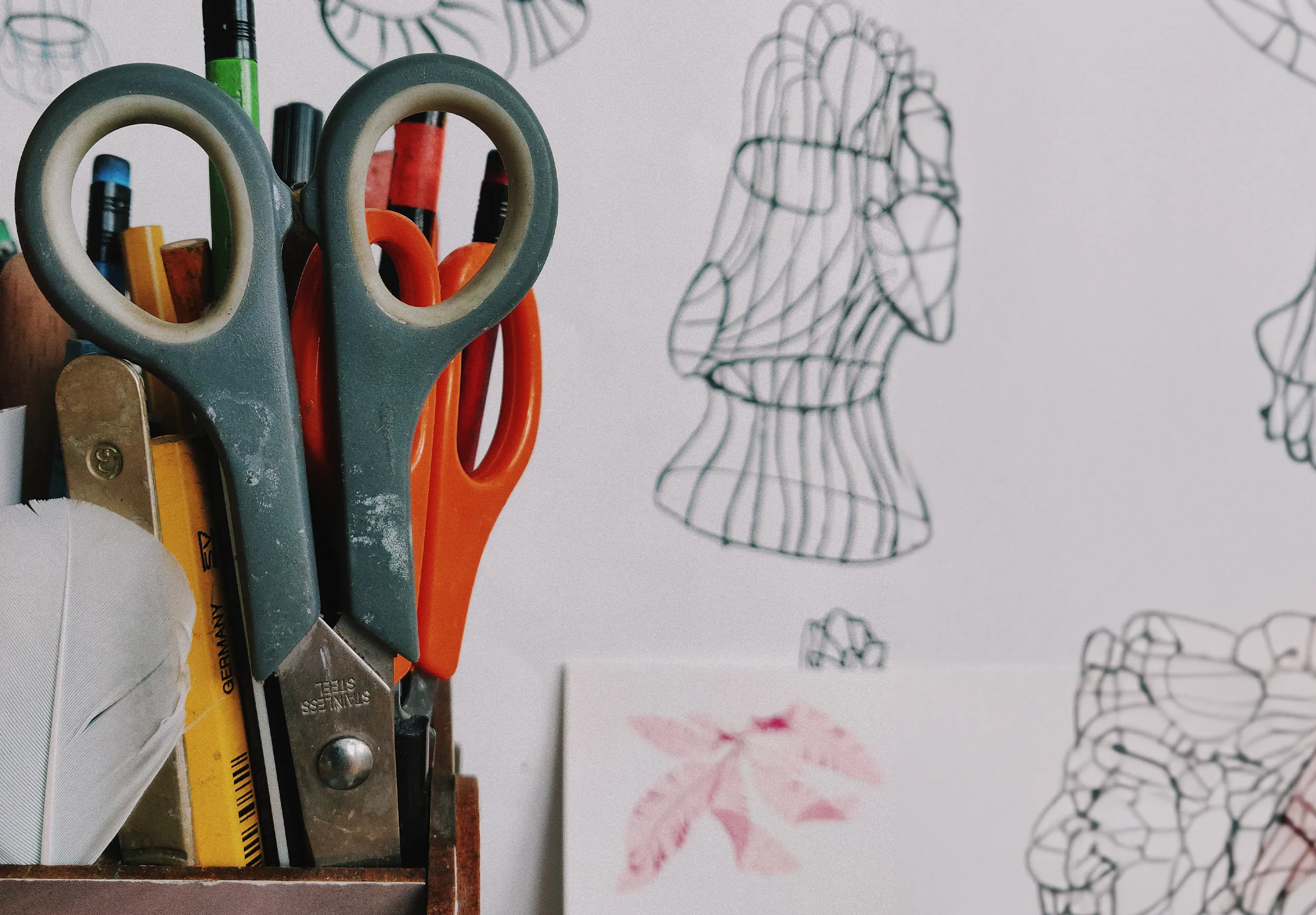 scissors in a pot with sketches in the background