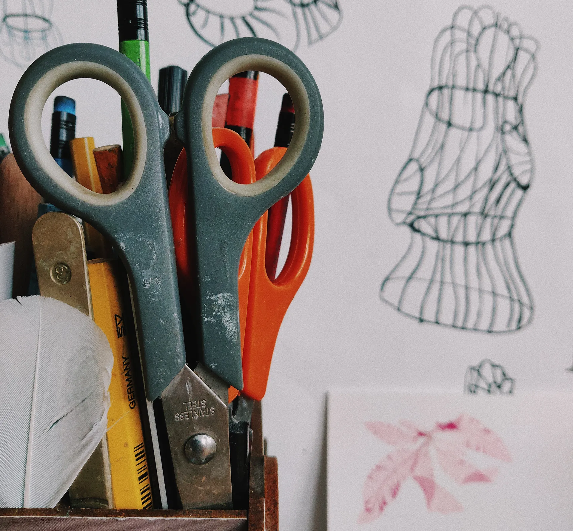scissors in a pot with sketches in the background