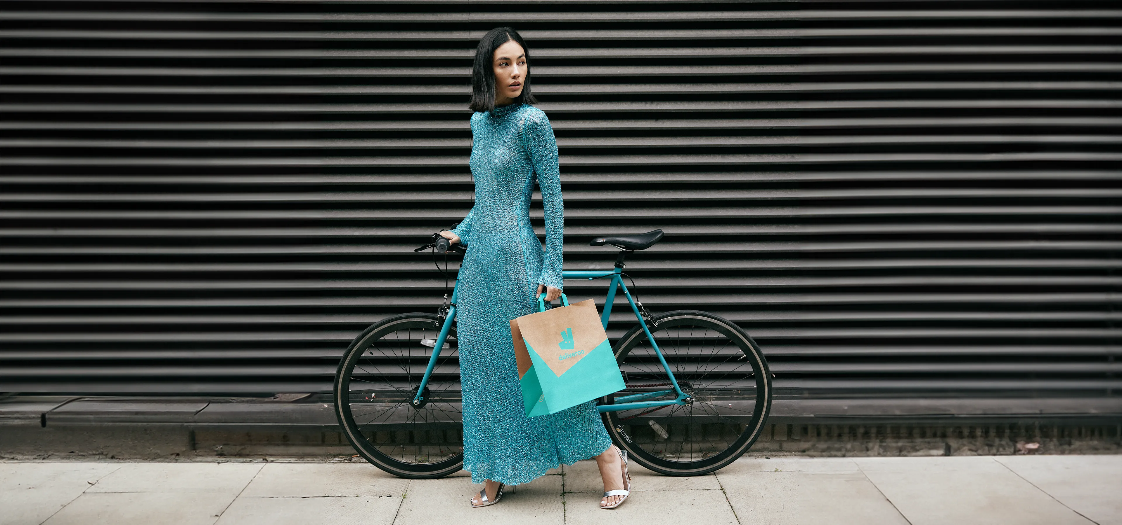 Woman in sheer dress holding a bag and a bike