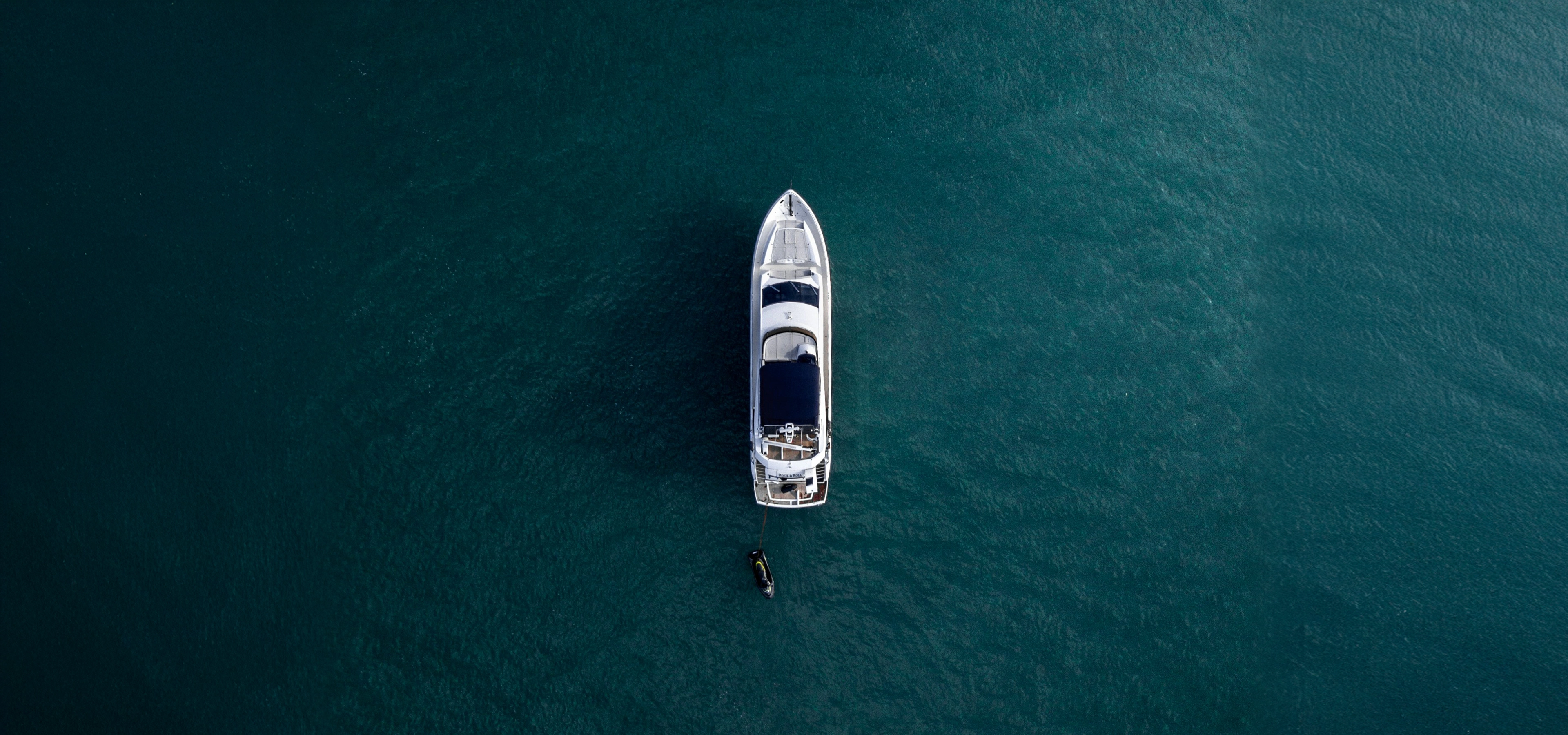 An image from above of a boat on a blue green sea
