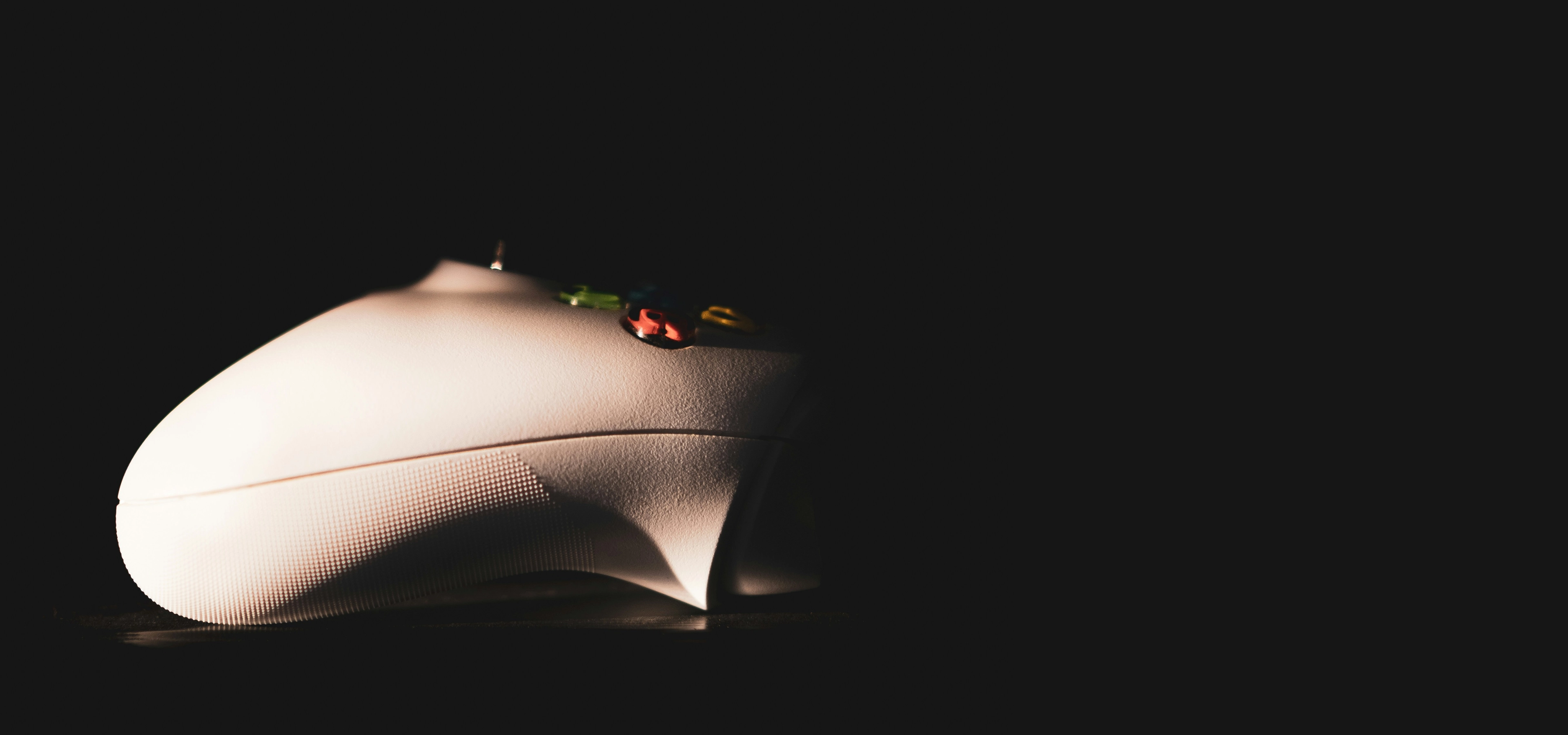 A white gaming controller on a black background