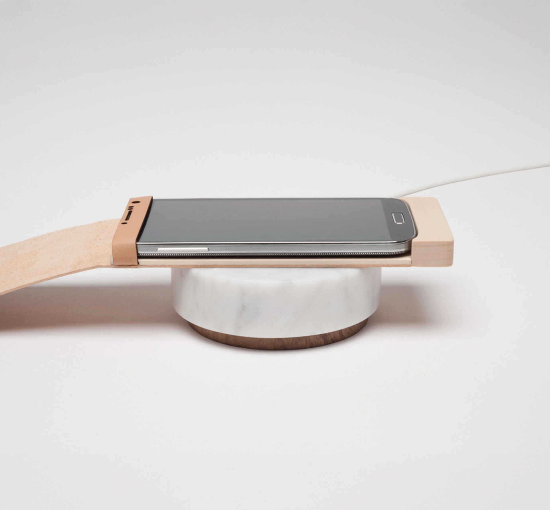 Phone in a wooden case on a marble charging base