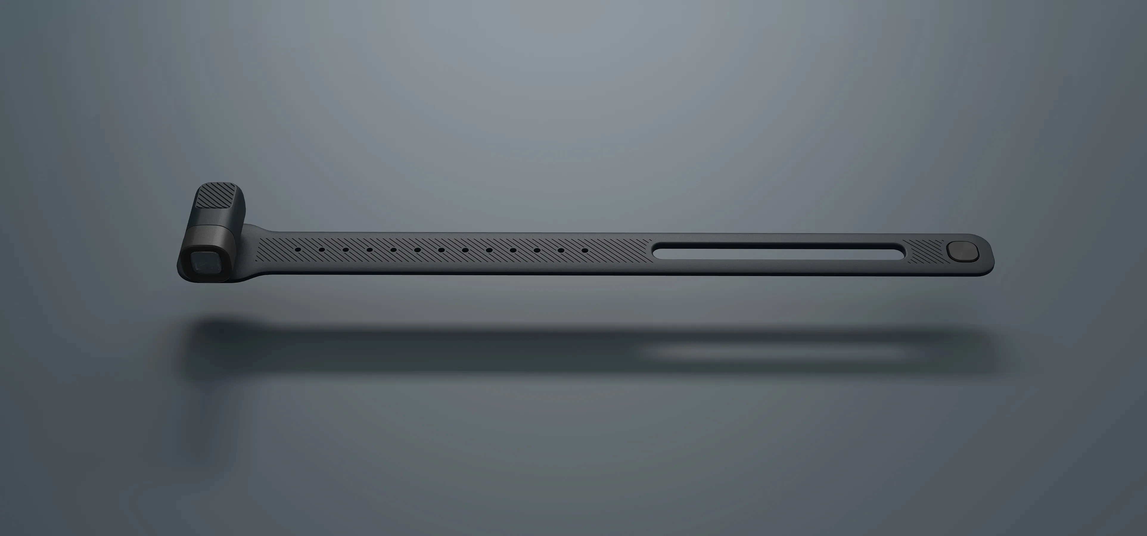 Image of a gray and black alva wearable torch in a flat-lay style composition. The product sits on a slate gray backdrop with a soft shadow.